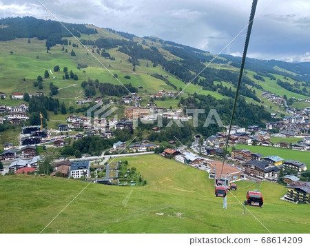 Aerial view on Hinterglemm village and mountains in Saalbach-Hinterglemm skiing region in Austria on a beautiful summer day from cableway on houses and holiday resorts Aerial view on Hinterglemm village and mountains in Saalbach-Hinterglemm skiing region in Austria on a beautiful summer day from cableway on houses and holiday resorts 68614209