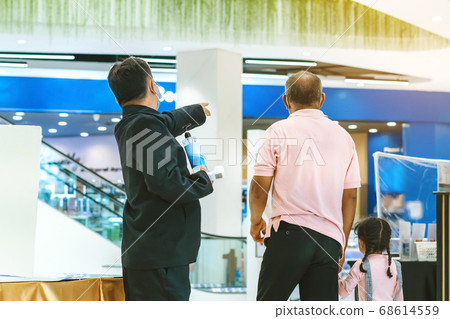 A male security guard wear face mask points out a way for customers to register their identity before entering the mall to prevent the spread of the Corona Virus (Covid-19). New normal lifestyle. 68614559