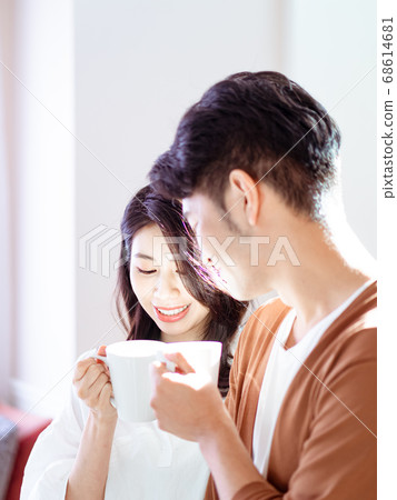 Young asian woman and man are enjoying spending time together at home with cup of coffee in hands. Young asian woman and man are enjoying spending time together at home with cup of coffee in hands. 68614681