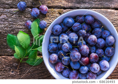 Plums in a bowl of a wooden background, top view. selective focus. space for copying text Plums in a bowl of a wooden background, top view. selective focus. space for copying text 68616493