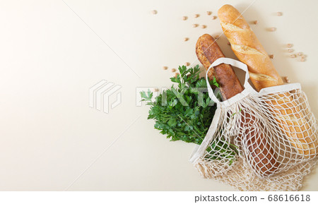 Mesh shopping bag with baguettes and fresh herbs top view with space for your text Mesh shopping bag with baguettes and fresh herbs top view with space for your text 68616618