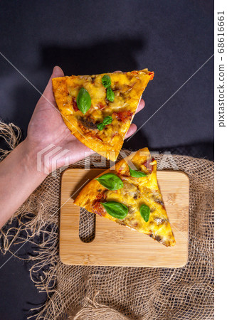 pizza Basil leaves on a black background, top view. vertical photo. Pizza with ham, meat, cheese, tomatoes and mushrooms. Two pieces. 68616661