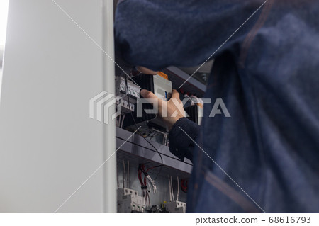 Industrial production of an electricity panel boards - man worker doing something with opened board 68616793