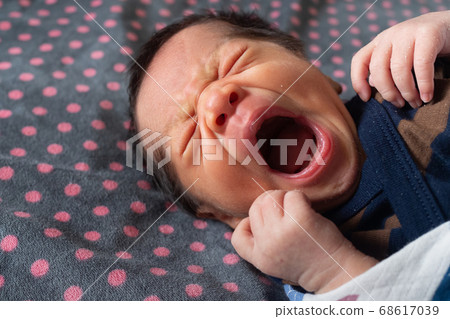 asian newborn baby boy with skin peeling still sleepy and yawning after wake up in the bedroom in the morning with warm sunlight in the summertime. family and baby lifestyle concept. 68617039