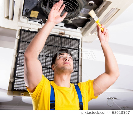 Repairman repairing ceiling air conditioning unit Repairman repairing ceiling air conditioning unit 68618567