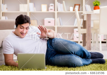 Man working on laptop at home on carpet floor 68618596
