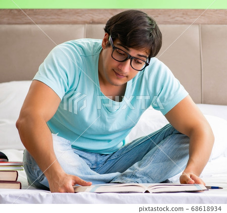 Student preparing for exams at home in bedroom sitting on the be Student preparing for exams at home in bedroom sitting on the be 68618934