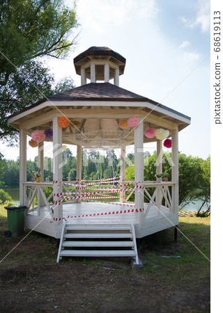 Outdoor gazebo decorated for a holiday. The entrance to the gazebo is blocked by signal tapes. Concept of quarantine during a pandemic. 68619113