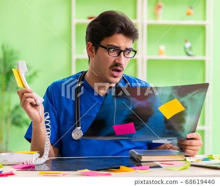 Young doctor sitting in hospital with many conflicting prioritie Young doctor sitting in hospital with many conflicting prioritie 68619440