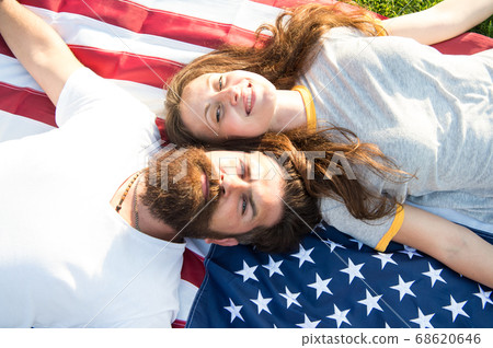 American couple relaxing on USA flag outdoors. 68620646