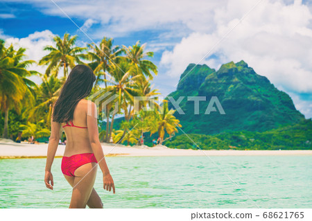 Travel paradise beach woman walking in water on beach on luxury holidays vacation Tahiti, Bora Bora. Beautiful sexy woman in red bikini girl on beach vacation in Tahiti, French Polynesia Travel paradise beach woman walking in water on beach on luxury holidays vacation Tahiti, Bora Bora. Beautiful sexy woman in red bikini girl on beach vacation in Tahiti, French Polynesia 68621765