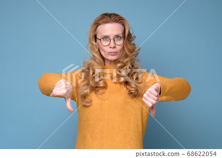 Gloomy dissatisfied mature woman looks at camera show thumbs down. Gloomy dissatisfied mature woman looks at camera show thumbs down. 68622054