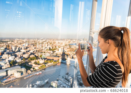 Tourist girl taking phone picture of sunset london skyline view from The Shard. Europe travel tourism Tourist girl taking phone picture of sunset london skyline view from The Shard. Europe travel tourism 68624018