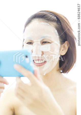 一個女人用面膜看著她的智能手機 一個女人用面膜看著她的智能手機 68624637