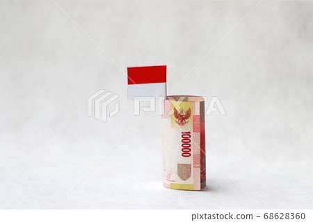 Rolled one hundred thousand banknote money of Indonesia Rupiah and mini Indonesia flag 68628360