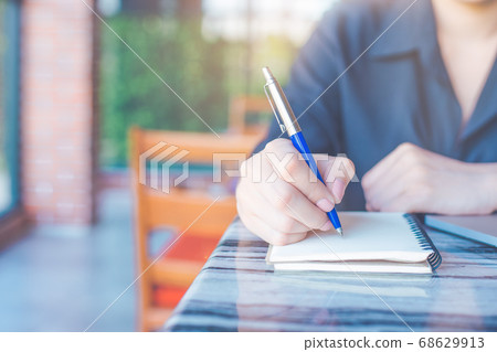 Woman is writing on a notebook with a pen 68629913