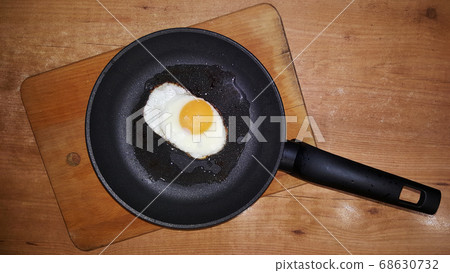 fried eggs from one egg in a black frying pan on a 68630732