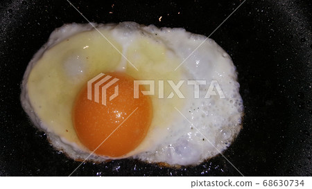 fried eggs from one egg on a black frying pan 68630734