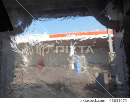 A gas station visible through the windshield while the car is being washed. A gas station visible through the windshield while the car is being washed. 68631073