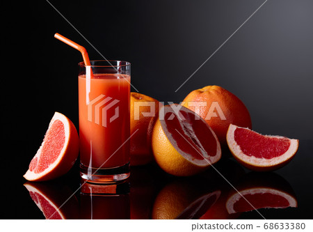 Glass of grapefruit juice and cut fruits on black Glass of grapefruit juice and cut fruits on black 68633380