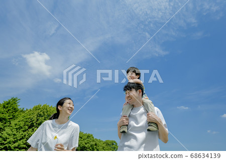 Three-person family playing in the park Three-person family playing in the park 68634139