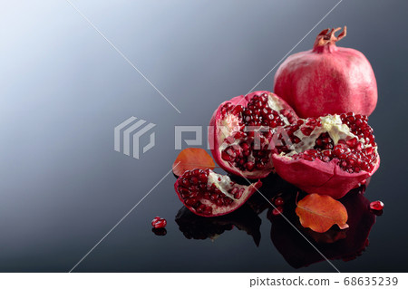 Ripe pomegranate fruits on a black reflective Ripe pomegranate fruits on a black reflective 68635239