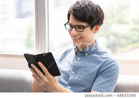 沙發照片素材上看智慧型手機的男人 68635500