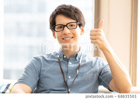 一個男人在沙發上豎起大拇指照片素材 68635501