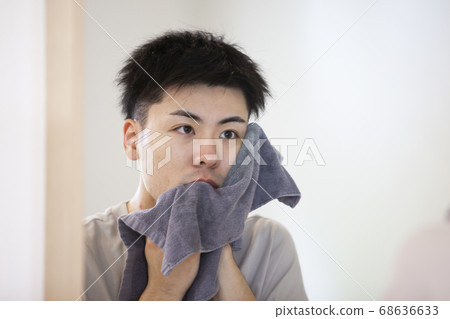 A man wiping his face with a towel 68636633