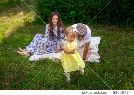 Cheerful little baby girl runs out of her parents at the picnic time at the garden 68636724