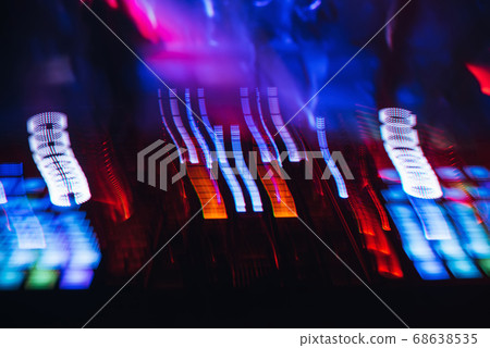 DJ mixer in a nightclub with glowing colored lights from controllers and buttons in the nightclub 68638535
