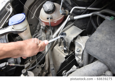 Mechanic checking and fixing a broken car in car 68639275