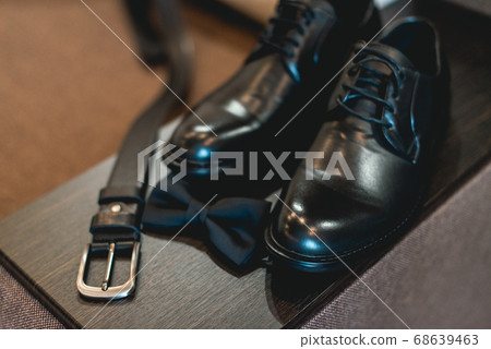 Close up of modern man accessories. Black bow tie, leather shoes and belt Close up of modern man accessories. Black bow tie, leather shoes and belt 68639463