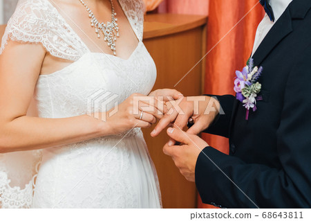 bride puts a gold wedding ring on the finger of the groom bride puts a gold wedding ring on the finger of the groom 68643811