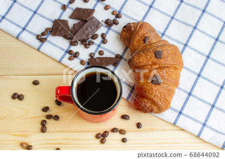 Coffee and a croissant on a wooden background. Coffee and a croissant on a wooden background. 68644092
