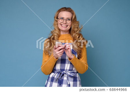 Caucasian mature woman in an apron looks into the phone smiling 68644966