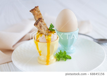 Boiled eggs in eggcups with spices, herbs and toasted bread for breakfast Boiled eggs in eggcups with spices, herbs and toasted bread for breakfast 68645156