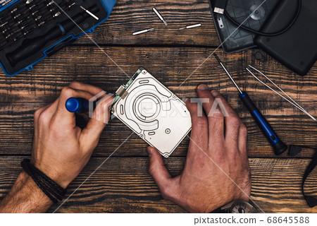 Two Hands with Screwdriver Disassemble HDD 68645588