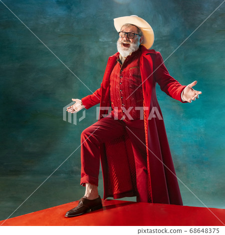 Modern stylish Santa Claus in red fashionable suit and cowboy's hat on dark background 68648375