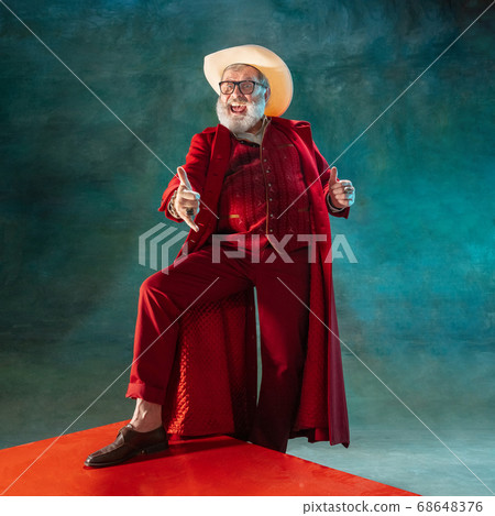 Modern stylish Santa Claus in red fashionable suit and cowboy's hat on dark background 68648376