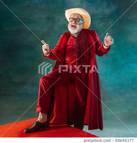Modern stylish Santa Claus in red fashionable suit and cowboy's hat on dark background 68648377