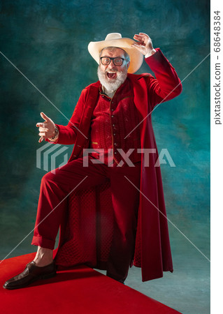 Modern stylish Santa Claus in red fashionable suit and cowboy's hat on dark background 68648384