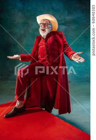 Modern stylish Santa Claus in red fashionable suit and cowboy's hat on dark background 68648385