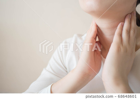 Female checking thyroid gland by herself. Close up of woman in white t- shirt touching neck. Thyroid disorder includes goiter, hyperthyroid, hypothyroid, tumor or cancer. Health care. Copy space. 68648601