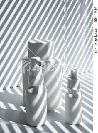 Three white plastic and glass vials in rays of the sun 68649343