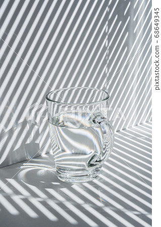 Still life with a glass mug and diagonal striped shadow 68649345