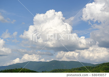 The white clouds have a strange shape and moutain.The sky and the open space have mountains below.Clouds floating above the mountains. The white clouds have a strange shape and moutain.The sky and the open space have mountains below.Clouds floating above the mountains. 68649857