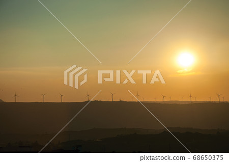 Landscape and several wind turbines silhouettes on sunset Landscape and several wind turbines silhouettes on sunset 68650375