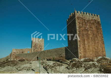 Stone wall and square tower from castle 68650402