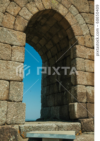 Arched gateway on stone wall over rocky hill Arched gateway on stone wall over rocky hill 68650409